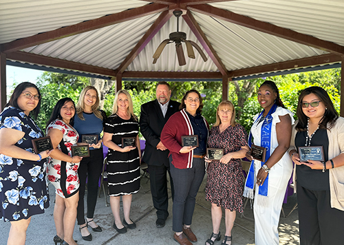 Group of happy teachers holding award plaques outside